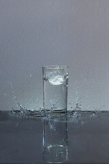Throwing ice into a glass of water, splashing water.