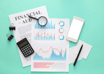 Business charts, mobile phone and stationery on green background