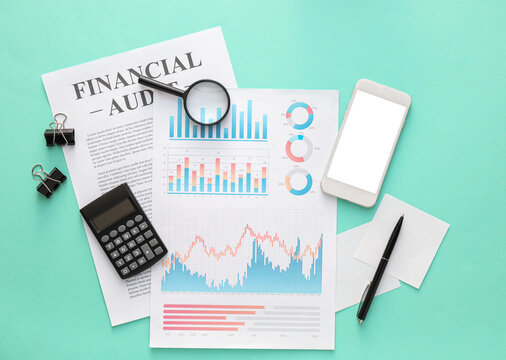 Business charts, mobile phone and stationery on green background