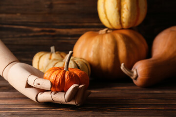 Mannequin hand with pumpkin on wooden background