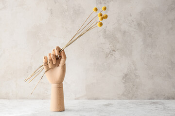 Wooden hand with flowers on light grunge background