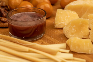 Various varieties of cheese, walnut kernels, smoked quail eggs and honey in a glass vase on a wooden surface