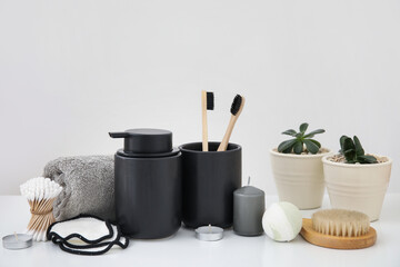 Set of different bath supplies with candles and houseplants on light background