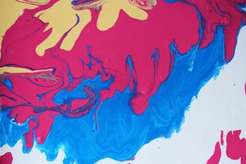 Abstract white-yellow-red-blue marble background. Acrylic paint spreads freely and creates an interesting pattern. Background for the cover of a laptop, notebook.