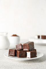 Plate with tasty bird's milk candies on light background