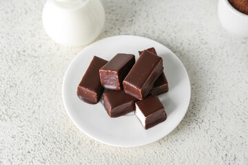 Plate with tasty bird's milk candies on light background