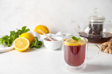 Fototapeta na wymiar Glass cup of black tea with lemon and mint on white table, closeup