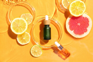 Bottles of vitamin C serum and fruits in water on color background - obrazy, fototapety, plakaty