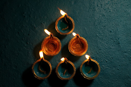 Happy Diwali Festival of Lights teal color background with teal and golden color traditional clay oil lamps Diya lit during Deepavali celebration, wallpaper, image, concept, backdrop.