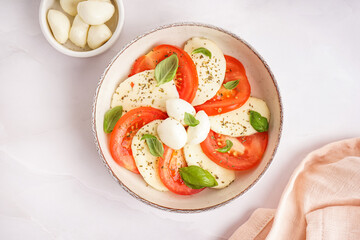 Bowl of tasty caprese salad on light background