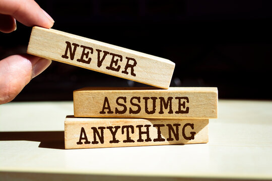 Wooden blocks with words 'Never Assume Anything'.