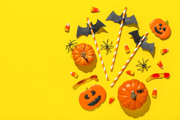 Paper bats with straws and Halloween treats on yellow background