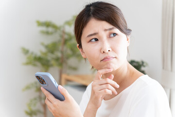 スマホを見て困った顔の女性