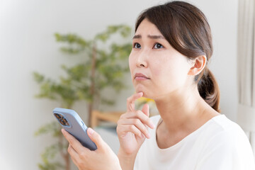 スマホを見て困った顔の女性