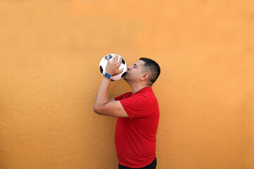 Latino adult man plays with a soccer ball very excited that he is going to see the World Cup and...