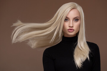 Portrait of a beautiful girl with long airy hair. Brown background.
