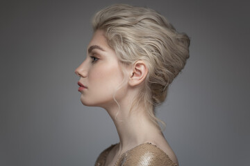 Fashion portrait of a beautiful girl with a bun hairstyle. Gray background.