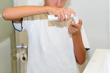 Preteen puts cream on her finger with a bottle in the bathroom. Close up view