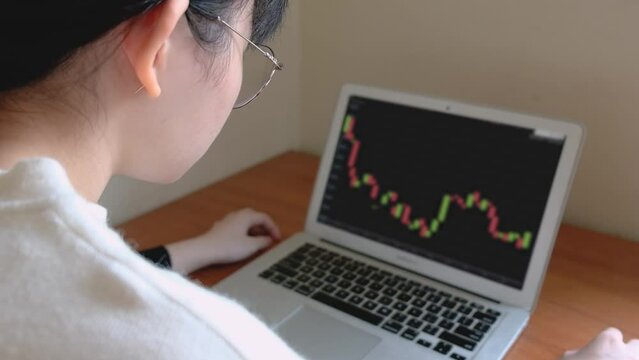 A girl looking over candlestick chart of Ethereum on a laptop  