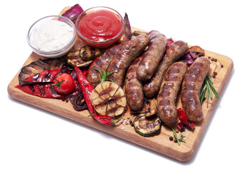 Grilled sausages and vegetables on wooden cutting board isolated on white background