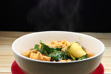 Traditional boiled tofu with peeled wax gourd seasoning with red curry serving in the bowl. Famous hot and spicy soup vegetarian menu in Asia restaurant.