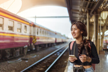 woman wearing black long sleeve t-shirt carrying backpack on shouder holding cellphone standing in railway station,travel concept,social network technology concept