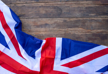 The flag of Great Britain made of silk is laid out on an old wooden table. Flat lay. Place for text