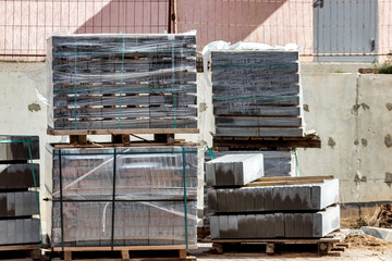 Pallets with gray paving slabs at a construction site. Plastic packaging protects the tiles from atmospheric effects. Preparation for installation. close-up. selective focus. Blurry background.