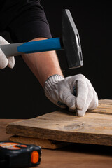 a man in work gloves hammers a nail with a hammer. Locksmith work