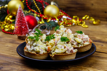 Traditional Russian festive salad Olivier in tartlets and Christmas decorations on wooden table