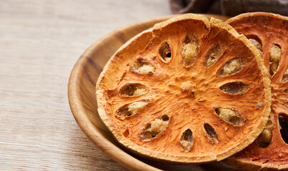 dry Indian bael fruit in wood plate on wooden table kitchen background. Indian bael fruit in wood plate. group of Indian bael fruit background                                                 