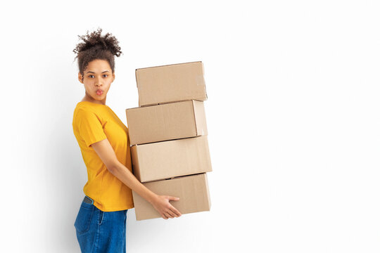 Young surprised woman African American woman with stack of cardboard boxes on white background. Copy space