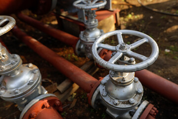 Shallow depth of field (selective focus) details with industrial metallic pipe valves used to open or close the hot water debit inside a big pipeline.