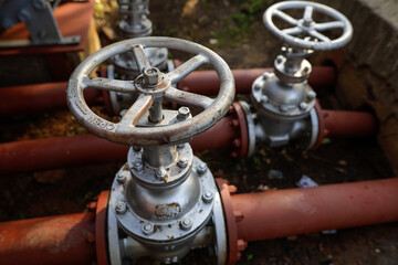 Shallow depth of field (selective focus) details with industrial metallic pipe valves used to open or close the hot water debit inside a big pipeline.