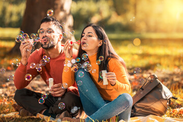 Young couple relaxing in the park with bubble blower.