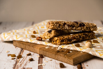 Various energy bars with granola chocolate in a row with scattered nuts, cereals and dried fruits, a grunge background of a white wood table. A healthy vegan snack for fitness. Close-up.