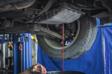 Auto mechanic draining an old transmission fluid out of the transmission.