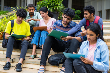 Group of students filling admission application form or preparing for exams on college campus by discussing eachother - concept of graduation, skill development and examination. - obrazy, fototapety, plakaty