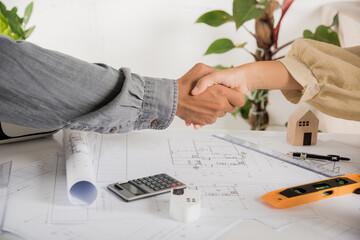 Architect team success and handshaking after meeting consult and work for architectural construction project with partner editing on blueprint paper plans, Architect and engineer shaking hands