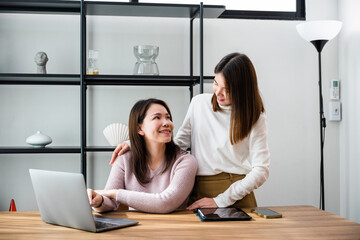 Asian middle age woman and teen they shoping online on computer, mother and teenage daughter looking at laptop computer at home office, happy family work together