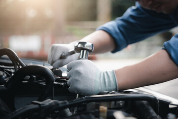 Service outdoor. Close up hands of auto mechanic man working on car engine using wrench to repair and maintenance, broken car care check and fixed the problem and services insurance