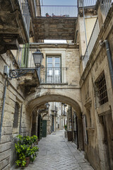 Fototapeta na wymiar Characteristic street in the historic center of Modica with a beautiful stone arch