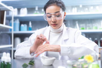 Beauty eco cosmetic research and development concept, Scientist or Pharmacist applying moisturizer lotion on her hand for efficacy testing of natural organic skincare products in laboratory