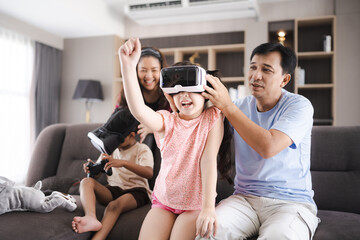 children family with mother and father home, happy and smile with virtual reality goggles technology together, person leisure lifestyle to having fun with digital video game by wearing headset