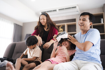 Fototapeta premium children family with mother and father home, happy and smile with virtual reality goggles technology together, person leisure lifestyle to having fun with digital video game by wearing headset
