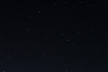 Naklejka na ściany i meble Many stars on black sky at night. A real dark night sky with plenty of stars. Night sky background with selective focus