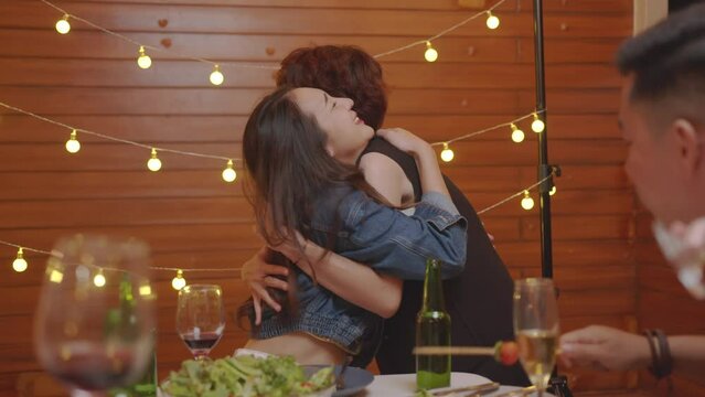 best friends hugging. young asian woman enjoying friendship hug at reunion gathering sitting at table having fun sharing weekend together relaxing