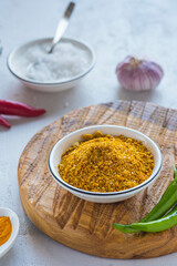 Spicy Svan salt in a white bowl on a wooden board on a light concrete background. Recipes for spices, spicy salt.