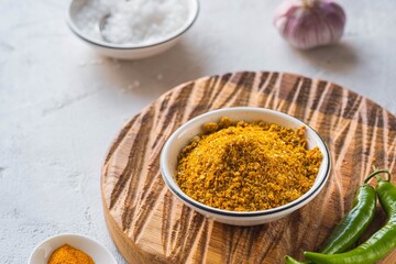 Spicy Svan salt in a white bowl on a wooden board on a light concrete background. Recipes for spices, spicy salt.