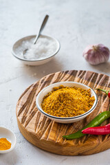 Spicy Svan salt in a white bowl on a wooden board on a light concrete background. Recipes for spices, spicy salt.